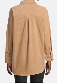 Kaki knappad skjorta med en bakficka, långa ärmar, enknappade manschetter och sluttande fåll. Mjuk tygtextur, minimalistisk design.