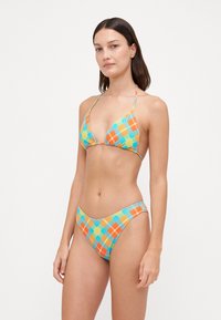Bikini set met een triangle top en een low-rise broekje, gemaakt van stof met een ruitjespatroon in blauwe, oranje en groene tinten.
