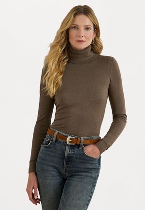 Brauner Rollkragenpullover aus weichem Stoff, kombiniert mit hellblauen Jeans und einem braunen Gürtel mit einer silbernen Schnalle.