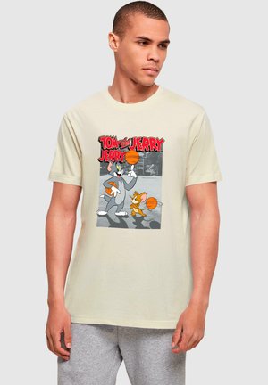 Beige Baumwoll-T-Shirt mit einem grafischen Druck von den Cartoon-Charakteren Tom und Jerry, die beide orangefarbene Basketballs halten, mit lebhaftem roten Text darüber.