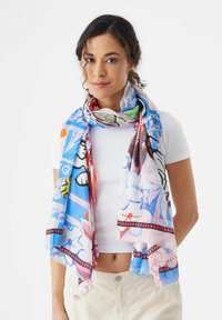 Écharpe légère et multicolore présentant un mélange de motifs en bleu, rouge, jaune et vert. Fabriquée en tissu doux et transparent. Les bords sont à franges.