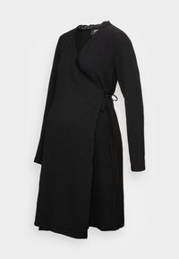 Vestido negro ajustado con mangas largas, tejido texturizado, borde de encaje en el escote y lazo lateral para el cierre.