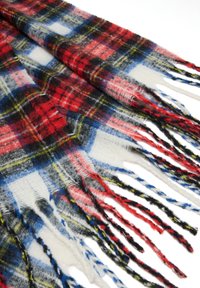 Écharpe écossaise rouge, noire et blanche avec des bords frangés ; texture douce ; présente des accents bleus et jaunes dans le motif à carreaux.