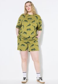 Completo da loungewear verde oliva composto da una maglietta a maniche corte e pantaloni corti abbinati, entrambi con una stampa animale ripetuta.