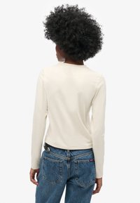 Biała bluzka z długim rękawem i okrągłym dekoltem, połączona z niebieskimi dżinsami o wysokim stanie z klasycznym pięciopocketowym krojem.