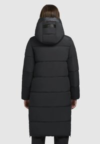 Zwarte pufferjas met een capuchon, voorzien van een doorgestikt ontwerp, een gladde textuur en een logo-accent op de achterkant. De lengte reikt tot halverwege de dij.