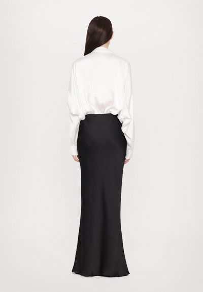 White satin blouse with loose fit and long sleeves, paired with a form-fitting black maxi skirt. Smooth texture overall, minimalist design.