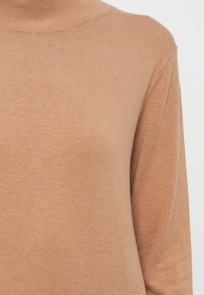 Pruunist nöörist kootud sviiter kõrge kaelusega ja pikkade varrukatega. Kanga pind näib pehme ja kerge tekstuuriga. Ilma nähtavate mustrite või detailideta.