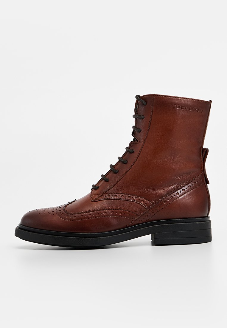 Braune Leder-Ankle-Boots mit traditioneller Broguemusterung, runder Spitze, Schnürung vorne und einer flachen schwarzen Gummisohle.