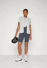 Sieviešu riteņbraukšanas apģērbs, kas sastāv no gaiši pelēka īsām piedurknēm džersija un tumši zilām biksēm. Iekļauts arī ķiveres un baltas riteņbraukšanas kurpes ar akcentiem.