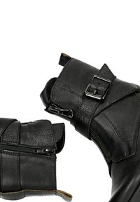 Černé kožené kotníkové boty s texturovaným povrchem, vybavené bočním zipem a detailem se sponou. Design je elegantní a ostrý.