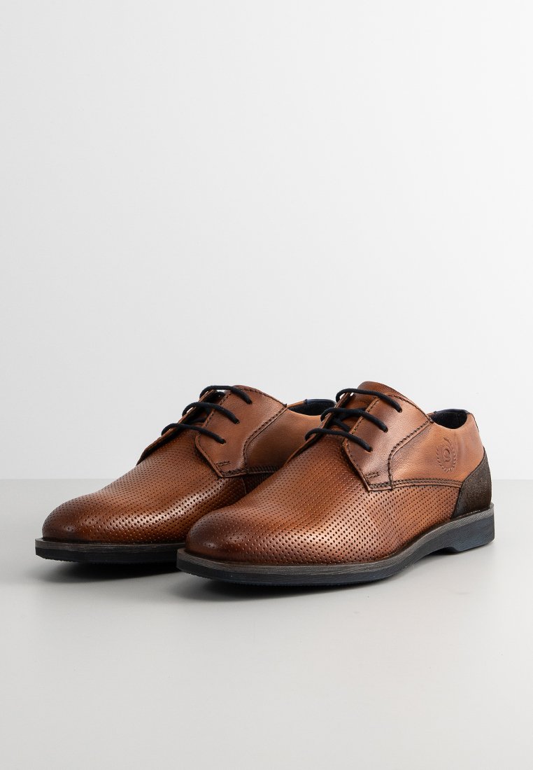 Zapatos de cuero marrón con diseño perforado, cordones negros y un tacón oscuro en contraste. Cuentan con una punta redonda y suela plana.