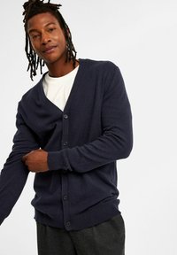 Dunkelblauer Cardigan mit V-Ausschnitt, langen Ärmeln und fünf Kn�öpfen vorne. Hergestellt aus weichem, strukturiertem Strickmaterial.
