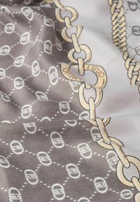 Écharpe en soie présentant un arrière-plan gris clair avec un motif de chaîne en crème et blanc, affichant une texture lisse et un éclat subtil.