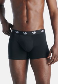 Svart boxerkalsonger med elastisk midja och vita Adidas-logodetaljer. Tillverkade av mjukt, stretchigt tyg för komfort.