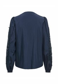 Blusa blu navy con maniche lunghe caratterizzate da dettagli in pizzo intricati e un tessuto liscio e testurizzato. Chiusura con bottone ai polsini.