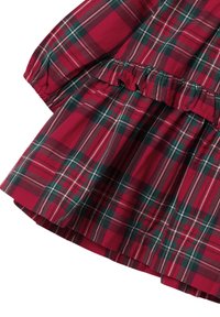 Punainen ja vihreä ruudullinen kangas, jossa on joustava rannetuki ja kerroksellinen rypytys yksityiskohtana pitkähihanaisessa vaatteessa.