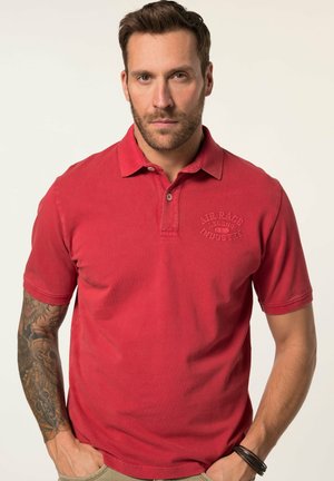 Rød polo shirt med krave og korte ærmer. Har "AIR RACE LEGEND INDUSTRY" broderet i matchende farve på brystet.