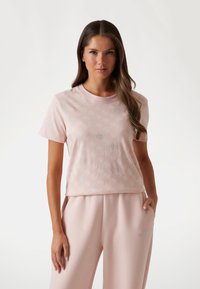 Light pink cotton t-shirt with a relaxed fit, featuring subtle silver patterned accents. Paired with matching light pink lounge pants.