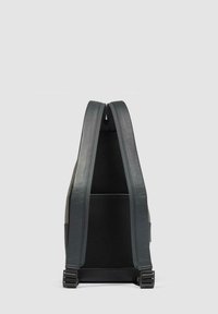 Vista trasera de una mochila gris de textura suave, con correas acolchadas, respaldo de malla y herrajes ajustables. Presenta un diseño elegante y minimalista.