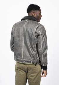 Graue Lederjacke mit einem Kragen aus Kunstfell, gerippten Manschetten und Nähten. Verfügt über ein kurzes Design und eine subtile Textur.
