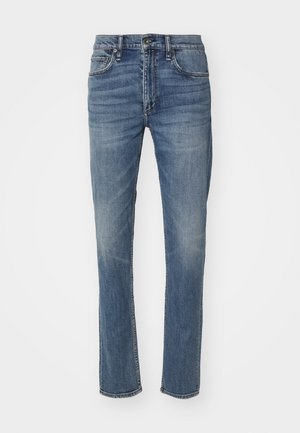 Sinine denimist teksapüks, sirge säärega, varustatud nööbi ja tõmbluku sulgemisega, nagu ka tavalise viie taskuga disainiga. Pleekinud viimistlus kerge hõõrdumisega.