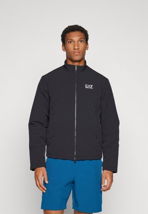 Giacca nera con zip e colletto alto, dotata di tasche laterali e logo EA7 sul lato sinistro del petto. Tessuto liscio e resistente; design imbottito.