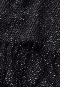 Tissu noir à motif chevron, avec des fils métalliques. La texture est tissée et lisse, avec des bords froncés qui ajoutent du détail.