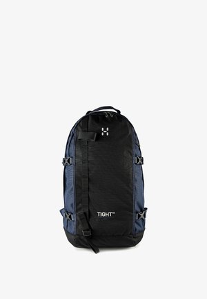 Sac à dos noir et bleu foncé avec sangles de compression latérales, boucle avant, poignée supérieure et logo "TIGHT" sur le panneau avant.