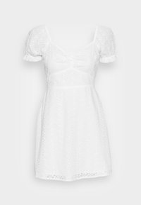 Vit klänning med puffärmar, prydd med broderi i ögonform och en figurnära bodice. Utsvängt kjol med en diskret volangkant.