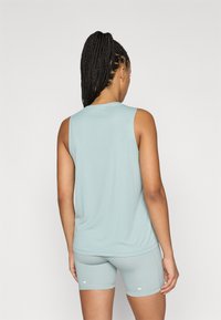 Hele sinine varrukateta pluus ümarate kaelustega, sobitatud sobivate lühikestega. Sile tekstuur ja keha jälgiv lõige.