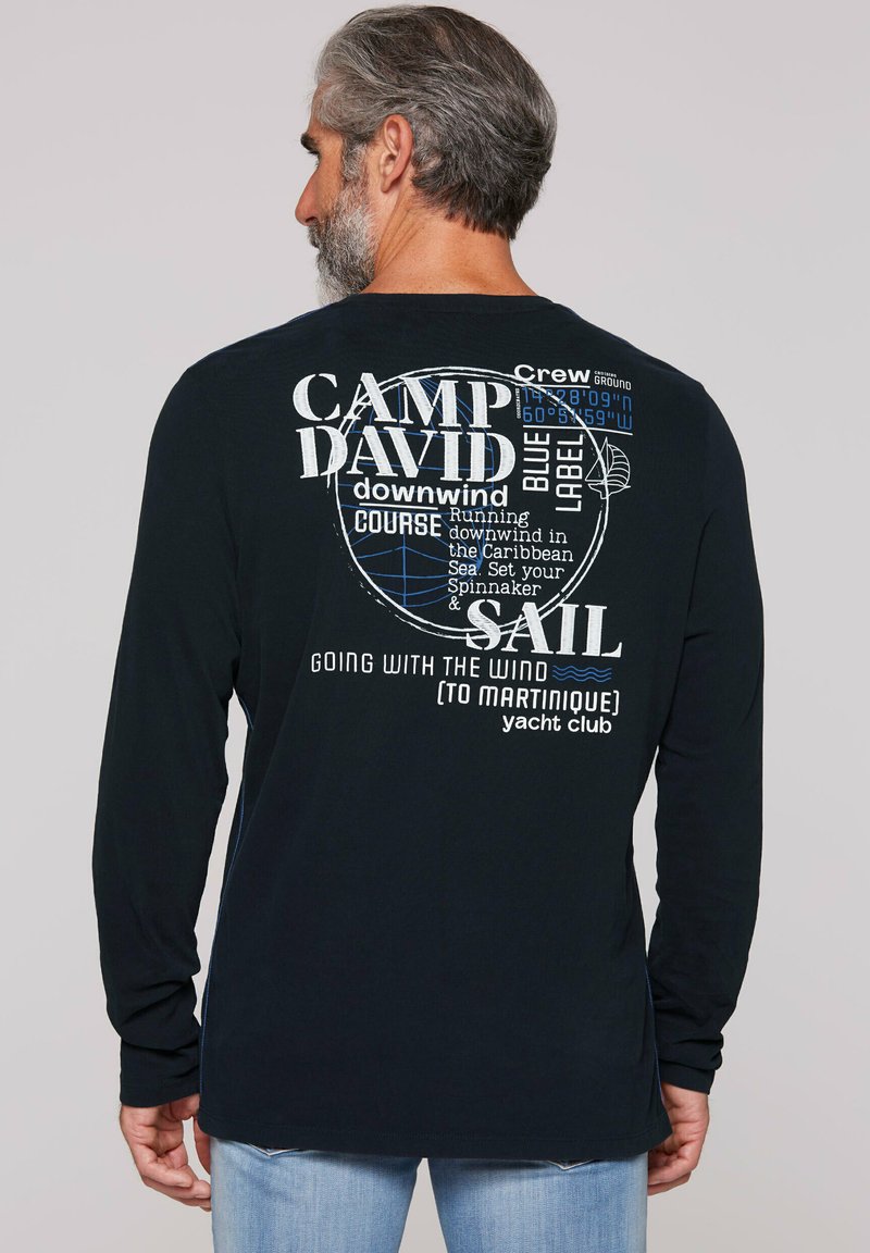 Langearmige marineblauwe T-shirt met witte en blauwe grafische tekst, met nautische thema's en de zinnen "CAMP DAVID" en "SAIL." Gemaakt van katoen.