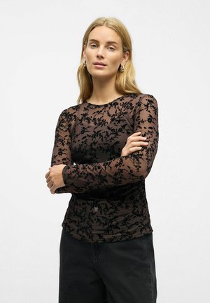 Sort langærmet top med blomstret spidsmodering, der har en rundt halsudskæring og tætsiddende silhuet, båret med mørke jeans.