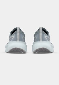 Chaussures de sport grises avec une finition lisse et texturée, présentant un design arrondi, un col rembourré et une semelle blanche épaisse avec une semelle à motif.