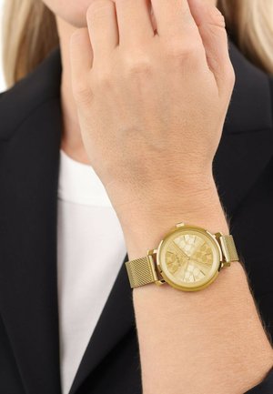 Goldene Netz-Armbanduhr mit einem goldfarbenen runden Gehäuse, strukturiertem Zifferblatt und verstellbarem Armband. Sichtbare Details auf dem Zifferblatt und der Schließe.