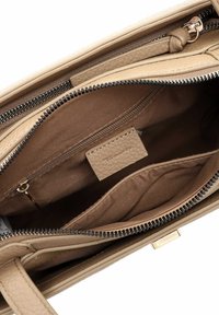 Beige læderhandtaske indvendig med blødt stoffor, der har en lynlåslomme og et ekstra rum til organisering.