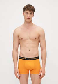 Boxeri portocalii dintr-un material moale, cu o curea neagră pe care este scris textul "JACK & JONES" în alb. Design simplu și ajustat.