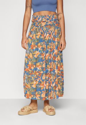 Květinová maxi sukně s živými pomerančovými a modrými květinovými vzory, elastickým pasem a měkkou látkou; doplněná béžovými sandály se zauzlením.