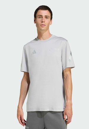 Lys grå sports T-shirt lavet af stof med korte ærmer, med rund hals og metalliske detaljer på skuldre og bryst.