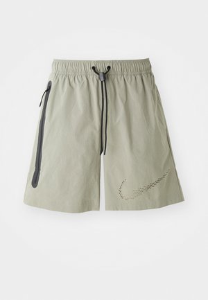 Light grey athletic shorts with an elastic waistband, drawstring, two side zip pockets, and a perforated logo detail on the lower left leg.