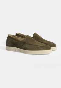 Olivgrüne Wildleder-Slipper mit runder Zehenpartie und cremefarbener Gummisohle, die sich durch minimale Nähte und eine glatte Textur auszeichnen.