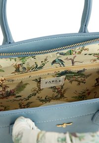 Lichtblauwe handtas met een gladde leren buitenkant. Interieur beschikt over een bloemenstofvoering met dierenillustraties, een gouden rits en een merklabel.