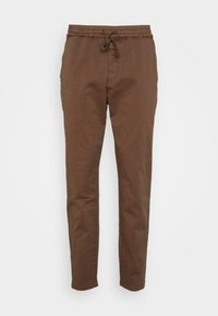 Braune Baumwoll-Jogginghose mit elastischem Bund, Kordelzug und schmal zulaufenden Beinen. Glatte Textur, keine sichtbaren Muster oder Akzente.