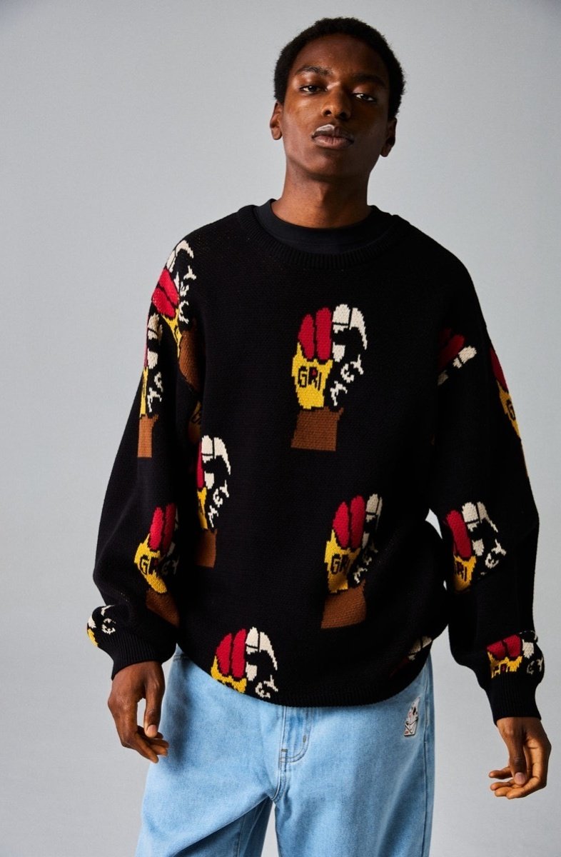 Suéter negro de punto con un patrón gráfico colorido de manos con guantes de diferentes colores. Corte holgado con un cuello y puños acanalados.