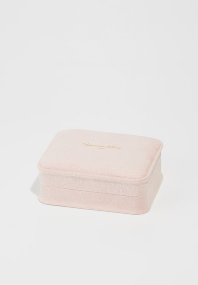 Cutie de bijuterii rectangulară, dintr-un material roz pal, cu o suprafață texturată și litere aurii pe capac, având margini rotunjite și o strălucire subtilă.