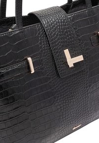 Sac fourre-tout en cuir noir gaufré crocodile avec une texture lisse, deux poignées et des éléments en métal doré mettant en avant un détail de fermoir central.