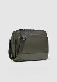 Borsa messenger in pelle verde con texture liscia, tracolla regolabile, scomparti con cerniera e logo Piquadro sul davanti.