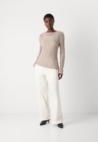 Beige ribbed knit sweater with long sleeves, round neckline; paired with white wide-leg trousers and black pointed-toe heels.