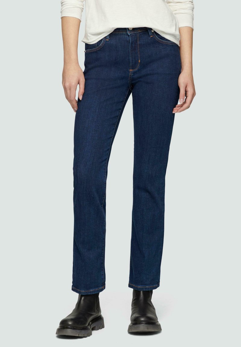 Granatowe dżinsy o dopasowanym kroju, wykonane z denimu. Posiadają pięć kieszeni i delikatne detalowanie za pomocą ściegów. W połączeniu z czarnymi botkami za kostkę.