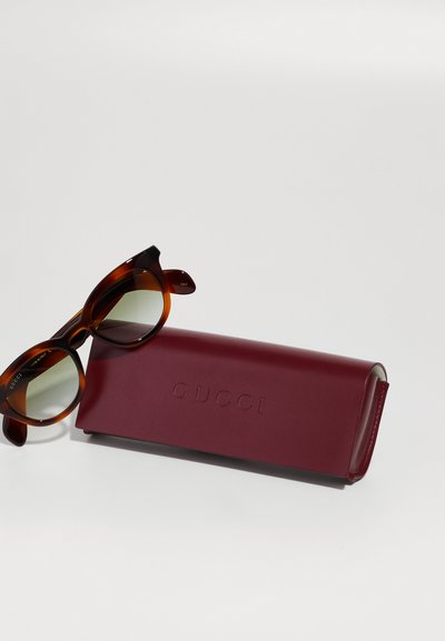 Gucci sunčane naočale s okvirom od kornjačevine, lećama s gradijentom i tamnocrvenom kožnom futrolom s utisnutim "GUCCI" sprijeda.